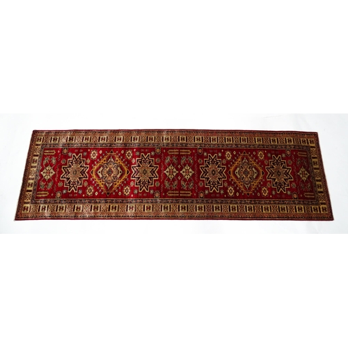 1317 - Carpet / Rug : A red ground runner decorated with repeating geometric motifs within banded geometric... 