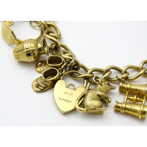 604 - A 9ct gold charm bracelet set with various 9ct gold and yellow metal charms to include penguin, iron... 