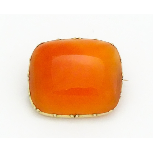 750 - A brooch set with orange carnelian within a yellow metal mount.  Approx. 1