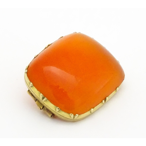 750 - A brooch set with orange carnelian within a yellow metal mount.  Approx. 1