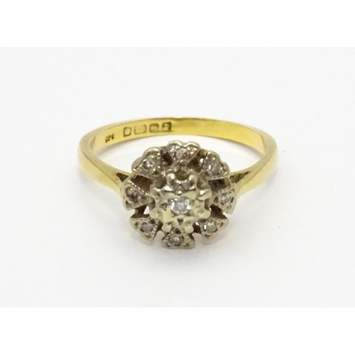 551 - An 18ct gold ring with nine illusion set diamonds in a floral setting. Ring size approx. K 1/2