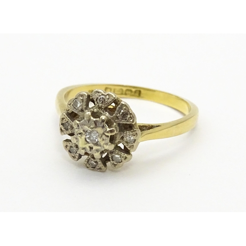 551 - An 18ct gold ring with nine illusion set diamonds in a floral setting. Ring size approx. K 1/2