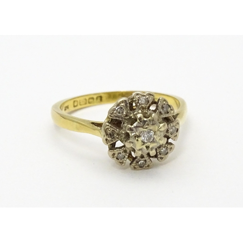 551 - An 18ct gold ring with nine illusion set diamonds in a floral setting. Ring size approx. K 1/2