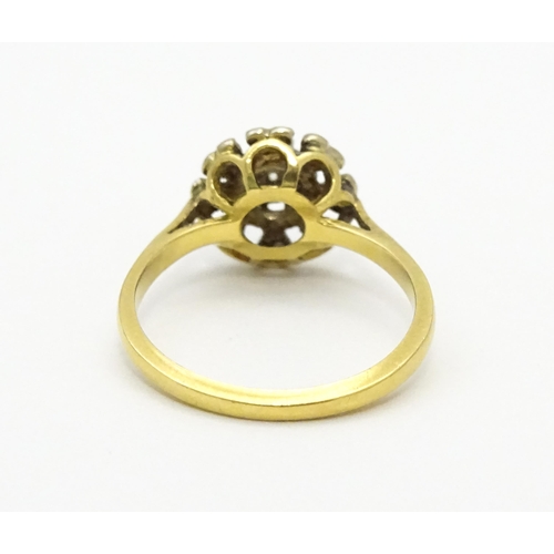 551 - An 18ct gold ring with nine illusion set diamonds in a floral setting. Ring size approx. K 1/2