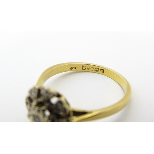 551 - An 18ct gold ring with nine illusion set diamonds in a floral setting. Ring size approx. K 1/2