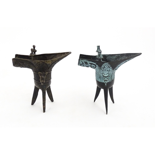 1048 - Two Chinese cast jue / ceremonial wine vessels with single zoomorphic handle, spout and raised on tr... 