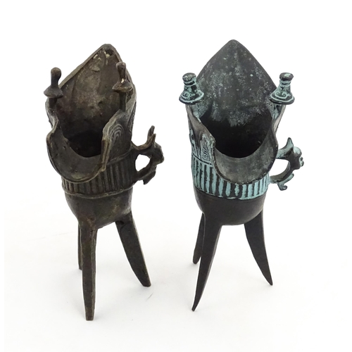 1048 - Two Chinese cast jue / ceremonial wine vessels with single zoomorphic handle, spout and raised on tr... 