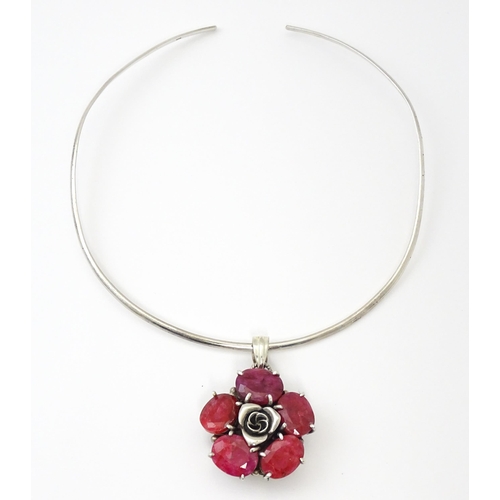 753 - A silver necklace of choker form with rose formed pendant set with red stones. The pendant approx 1 ... 