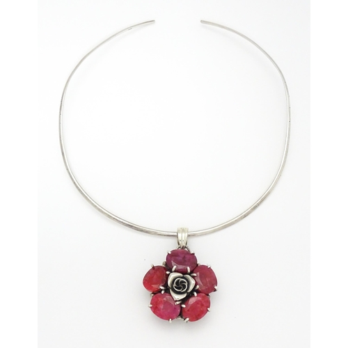 753 - A silver necklace of choker form with rose formed pendant set with red stones. The pendant approx 1 ... 