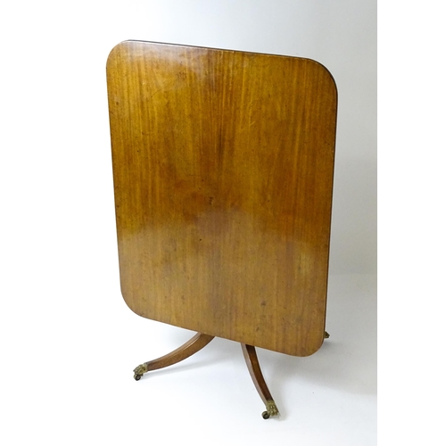 1440 - A Victorian mahogany breakfast table with an oblong tilt top above a turned pedestal and four sabre ... 