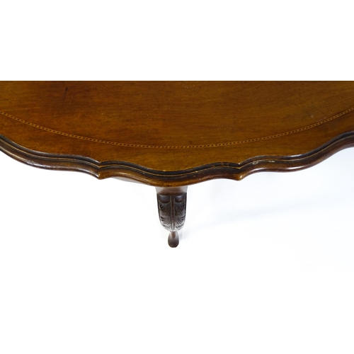 1472 - An Edwardian mahogany occasional table with a shaped inlaid top above four carved cabriole legs unit... 