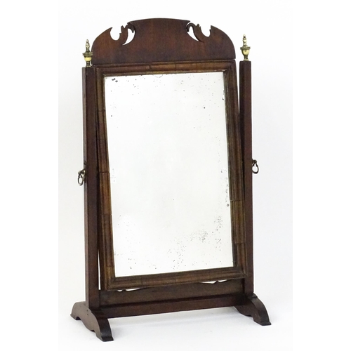 1477 - A 19thC walnut toilet mirror with a moulded frame, tapering uprights surmounted by brass finials and... 