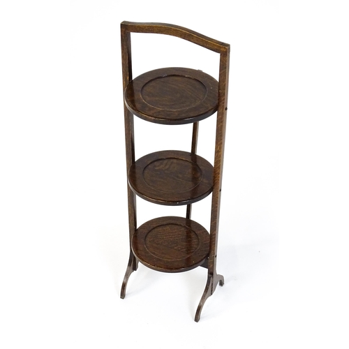 1480 - An early / mid 20thC folding oak cake stand with three circular dished tiers. 34