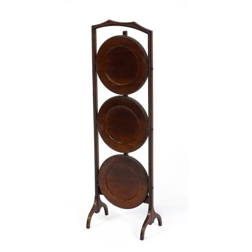 1481 - An early / mid 20thC mahogany folding cake stand, having three circular tiers with beadwork style mo... 