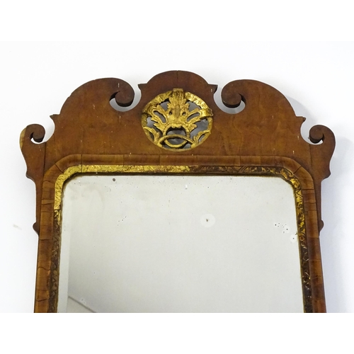 1488 - An 18thC walnut mirror with a scrolled top and gilt pierced floral decoration above a gilt moulded s... 