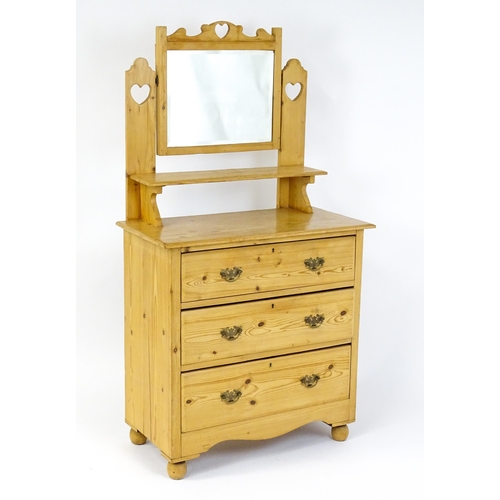 1493 - An early 20thC pine dressing table decorated with pierced heart shaped motifs, having a bevelled mir... 