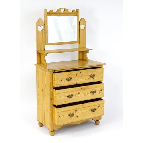 1493 - An early 20thC pine dressing table decorated with pierced heart shaped motifs, having a bevelled mir... 