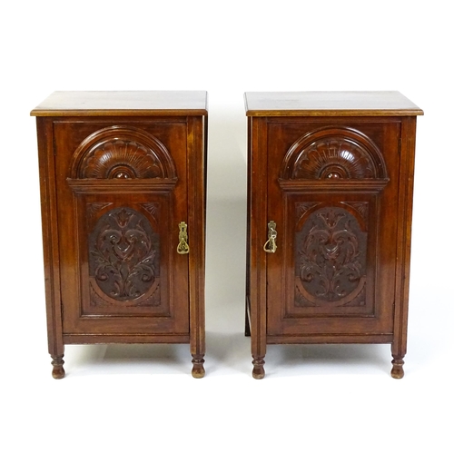 1495 - A pair of Edwardian walnut pedestals with moulded tops above carved panelled doors raised on turned ... 