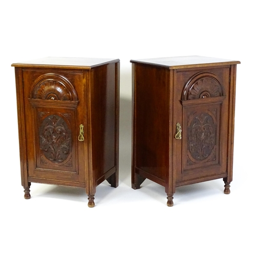 1495 - A pair of Edwardian walnut pedestals with moulded tops above carved panelled doors raised on turned ... 