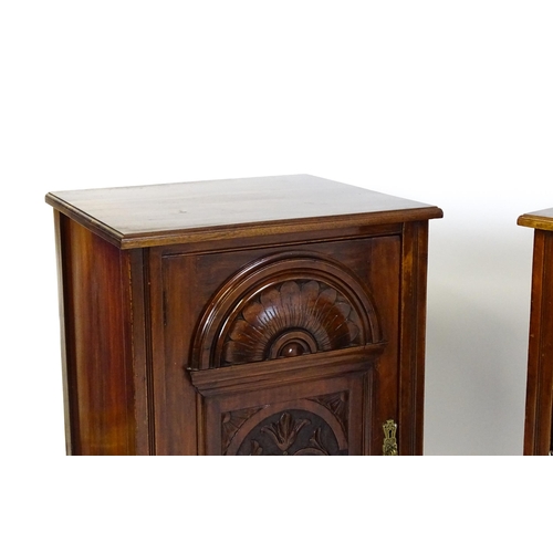 1495 - A pair of Edwardian walnut pedestals with moulded tops above carved panelled doors raised on turned ... 