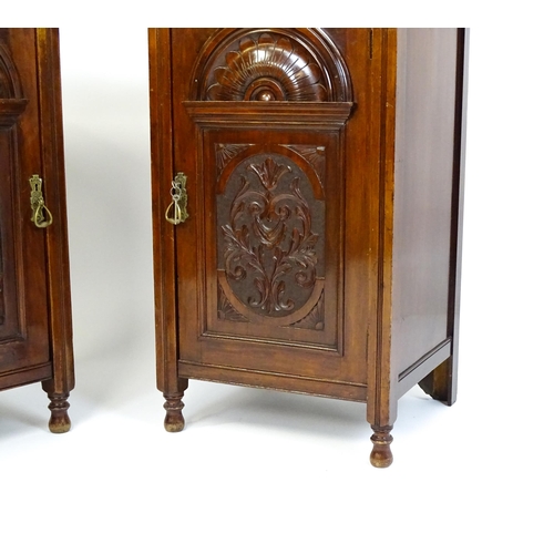 1495 - A pair of Edwardian walnut pedestals with moulded tops above carved panelled doors raised on turned ... 