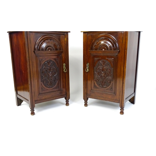 1495 - A pair of Edwardian walnut pedestals with moulded tops above carved panelled doors raised on turned ... 