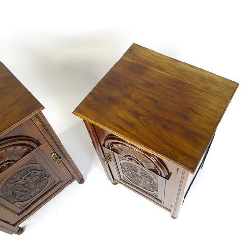 1495 - A pair of Edwardian walnut pedestals with moulded tops above carved panelled doors raised on turned ... 