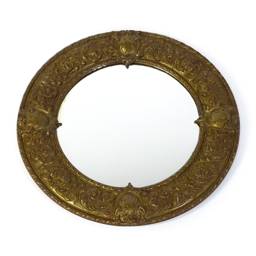 1482 - An early 20thC circular mirror with a brass embossed frame. 24