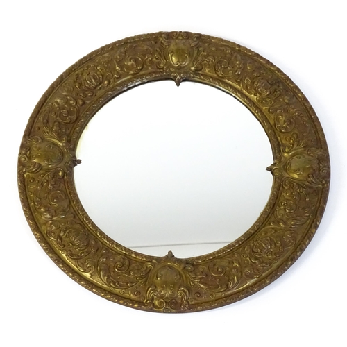 1482 - An early 20thC circular mirror with a brass embossed frame. 24