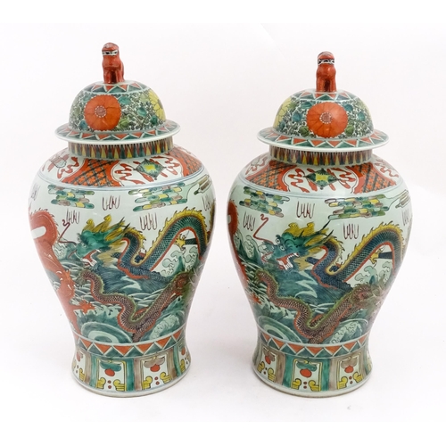 4 - A large pair of Chinese ginger jars decorated with dragons above stylised waves, bordered by flowers... 