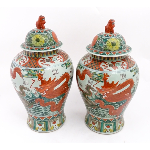 4 - A large pair of Chinese ginger jars decorated with dragons above stylised waves, bordered by flowers... 