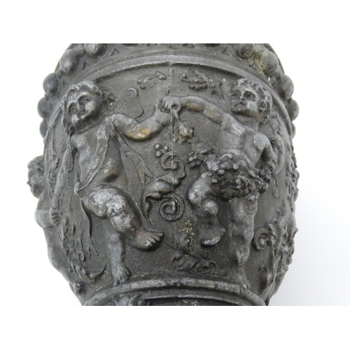 357 - A 20thC cast vase of goblet form decorated in relief with Bacchanalian putti. Approx. 9 3/4
