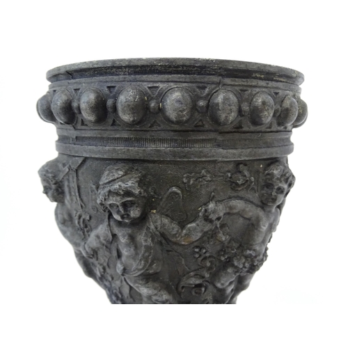 357 - A 20thC cast vase of goblet form decorated in relief with Bacchanalian putti. Approx. 9 3/4