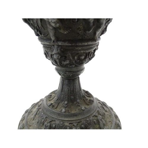 357 - A 20thC cast vase of goblet form decorated in relief with Bacchanalian putti. Approx. 9 3/4