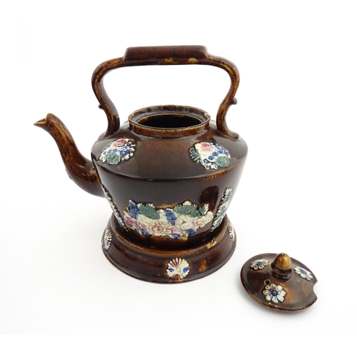 148 - A 19thC Measham bargeware teapot on stand decorated with flowers and foliage. Approx. 9 1/4