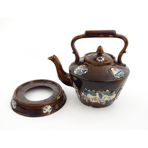 148 - A 19thC Measham bargeware teapot on stand decorated with flowers and foliage. Approx. 9 1/4