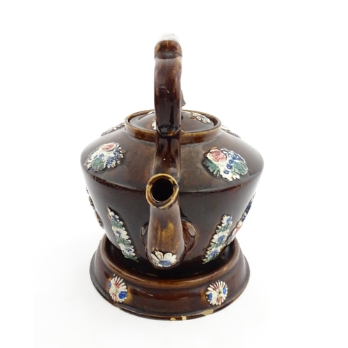 148 - A 19thC Measham bargeware teapot on stand decorated with flowers and foliage. Approx. 9 1/4