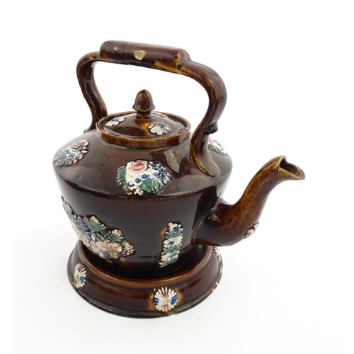 148 - A 19thC Measham bargeware teapot on stand decorated with flowers and foliage. Approx. 9 1/4