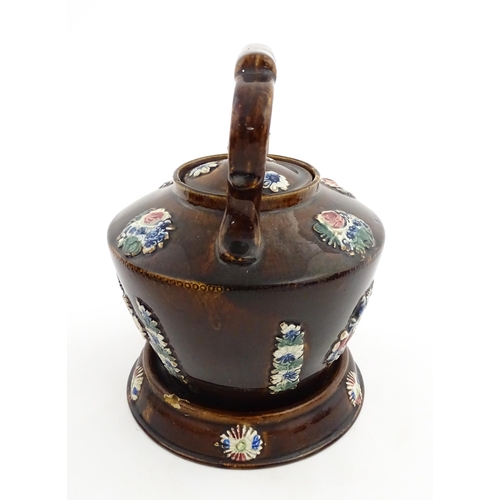 148 - A 19thC Measham bargeware teapot on stand decorated with flowers and foliage. Approx. 9 1/4