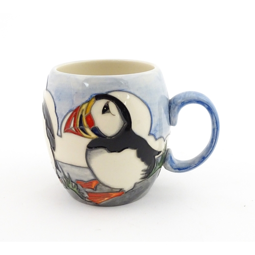 104 - A Moorcroft mug decorated with puffins. Marked under. Approx. 3 1/2
