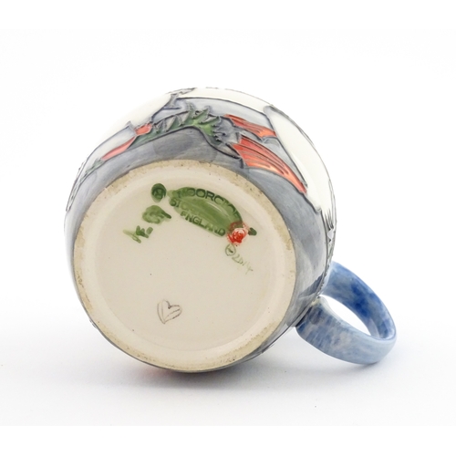 104 - A Moorcroft mug decorated with puffins. Marked under. Approx. 3 1/2