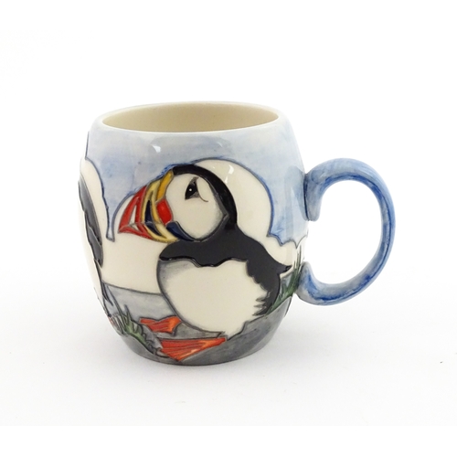 104 - A Moorcroft mug decorated with puffins. Marked under. Approx. 3 1/2