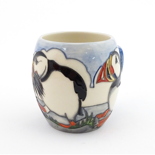 104 - A Moorcroft mug decorated with puffins. Marked under. Approx. 3 1/2