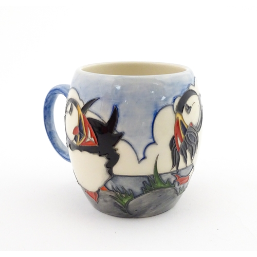 104 - A Moorcroft mug decorated with puffins. Marked under. Approx. 3 1/2