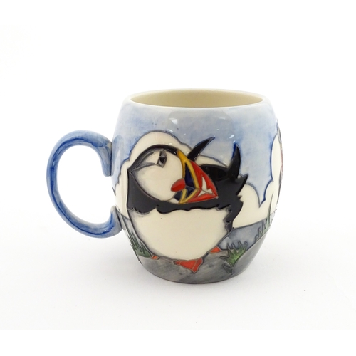 104 - A Moorcroft mug decorated with puffins. Marked under. Approx. 3 1/2