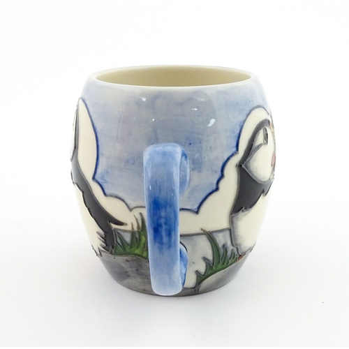 104 - A Moorcroft mug decorated with puffins. Marked under. Approx. 3 1/2