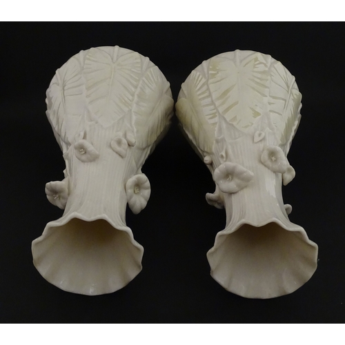 69 - A pair of Belleek vases in the Nile pattern having cala lily and foliate detail, with lustre highlig... 