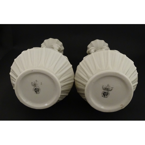 69 - A pair of Belleek vases in the Nile pattern having cala lily and foliate detail, with lustre highlig... 