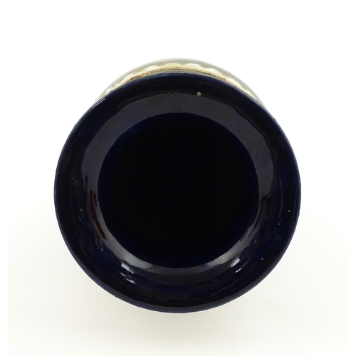 105 - A Royal Doulton vase with blue glaze and high relief dragon decoration to rim by Mark V Marshall. Ma... 