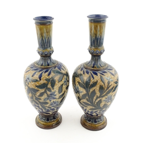 107 - A pair of Doulton Lambeth stoneware vases with  floral and foliate decoration. Marked under,  bearin... 